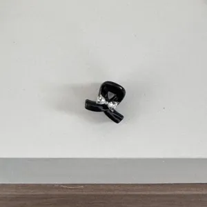 Closeup of a mini black bow hair claw clip with sparkling rhinestones for hairstyles.
