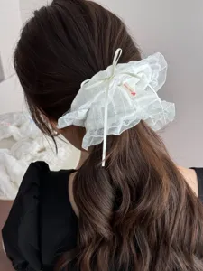 Weißes Haargummi Detail mit feiner Schleife und weichem Spitzenstoff für elegante Frisuren.