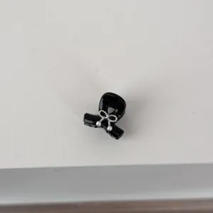 Detailed view of a mini black hair claw clip featuring a cute silver bow and pearl accents.