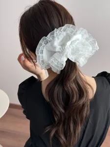 Detailaufnahme eines reinweißen Spitzen-Haargummis mit Schleife, elegant und sanft.