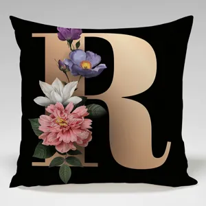 Close-up detail of the black square pillow cover featuring a gold letter R and flowers.