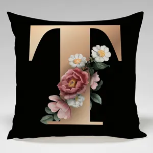 Close-up of black and gold letter T decorative cushion cover featuring vintage floral pattern.