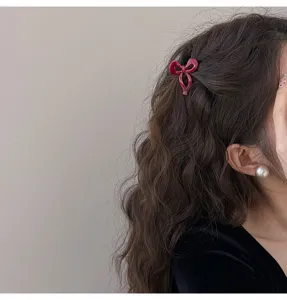 Primer plano de una pequeña pinza de pelo con lazo rojo, ideal para flequillos y peinados finos.