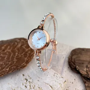 Detail view of women's rose gold quartz watch with sparkling rhinestone bracelet and clear stand.