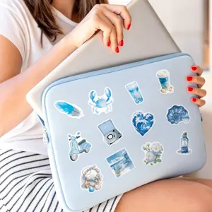 Detailed view of blue coastal aesthetic laptop sleeve decorated with watercolor ocean stickers.