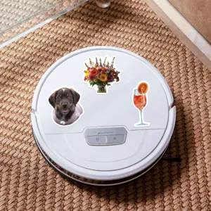 Detailed view of cute puppy flower and cocktail stickers applied on white robot vacuum cleaner surface.