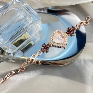 Detail view of women rose gold rhinestone heart quartz watch with elegant clover crystal bracelet.