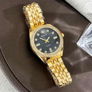 Goldene Quarzuhr Detail mit schwarzem Zifferblatt, Strasslünette und Metallarmband.