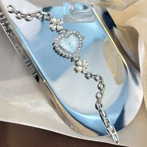 Silver heart-shaped rhinestone dial watch with clover charms and metal chain strap.