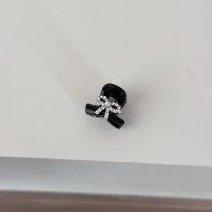 Close-up detail of a cute black mini hair claw clip featuring a sparkly rhinestone and pearl bow.