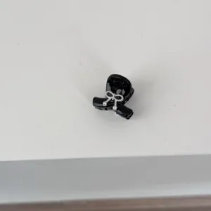 Close-up detail of a cute black mini hair claw clip featuring a sparkly silver crystal bow.
