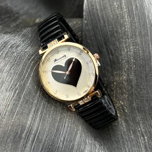 Damen Quarzuhr Detailaufnahme, schwarzes Herz Zifferblatt mit Strass Index, elastisches Band.