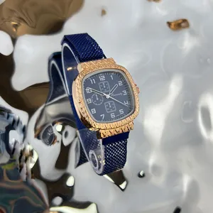 Nahaufnahme einer quadratischen Quarzuhr mit blauem Mesh-Armband und strukturiertem Gehäuse.