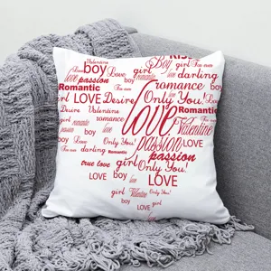 Gros plan d'une taie d'oreiller blanche avec typographie d'amour rouge sur canapé.