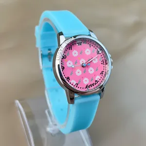 Nahaufnahme der Kinderuhr mit rosa Blumen-Zifferblatt und hellblauem Silikonarmband.