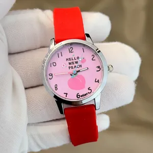 Nahaufnahme der Kinder Quarzuhr mit rosa Pfirsich Zifferblatt und rotem Silikonarmband.