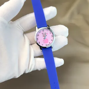 Nahaufnahme einer süßen Pfirsich-Zifferblatt-Uhr mit blauem Silikonarmband, Detailansicht.