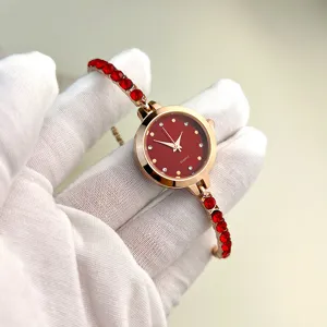 Exquisite women's quartz watch with red rhinestones and elegant gold bracelet band detail shot.