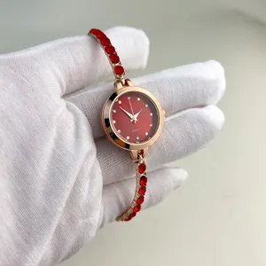 Detailed view of a women quartz watch featuring a red dial and crystal inlaid bracelet strap.