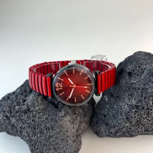 Vista detallada en primer plano de un reloj de cuarzo para mujer con correa elástica roja y esfera.