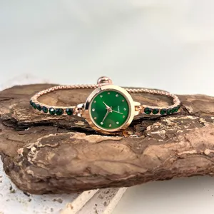 Close-up detail of women quartz watch with green dial and rhinestone bracelet strap.