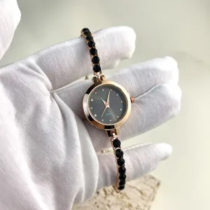 Close-up detail of women rose gold quartz watch with black crystal stones and elegant bracelet.