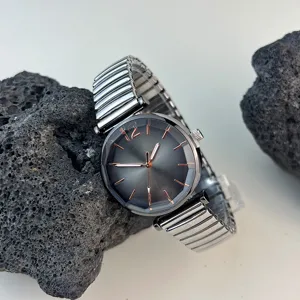 Reloj de cuarzo para mujer con correa elástica de metal y esfera oscura minimalista.