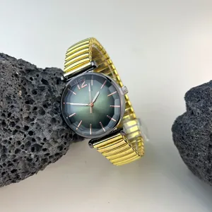 Reloj de cuarzo para mujer con esfera verde degradada y correa elástica dorada, estilo casual.