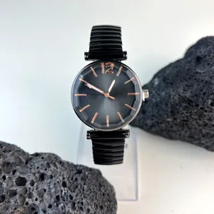 Elegante reloj de cuarzo para mujer con esfera negra y correa elástica de metal resistente.
