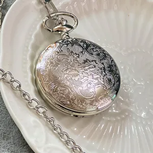 Primo piano dettagliato di un orologio da tasca al quarzo argentato con incisione floreale.