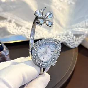 Close-up view of sparkling silver clover and teardrop rhinestone quartz bangle watch detail.