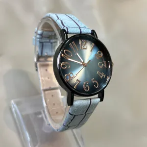 Vista detallada de reloj para mujer con esfera degradada y correa de cuero azul.