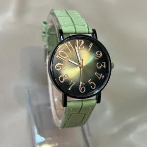 Detalle de reloj de cuarzo para mujer con esfera degradada verde y correa de piel.