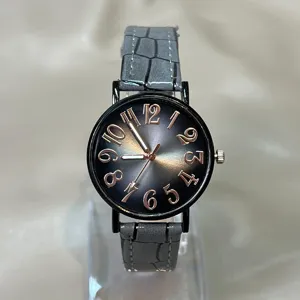 Detalle en primer plano de reloj de mujer con correa de cuero gris y esfera degradada negra.