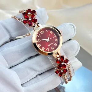 Close-up detail shot of women's rhinestone flower bracelet quartz watch with striking red dial.