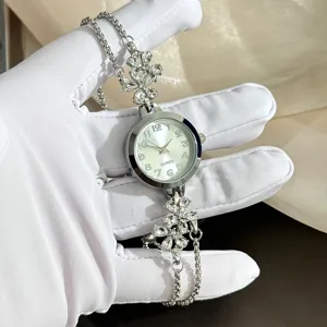 Women's rhinestone flower bracelet quartz watch with silver metal strap and numeric dial.
