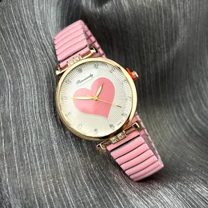 Nahaufnahme Detail der Damen Quarzuhr mit rosa elastischem Armband und Strass Herz Zifferblatt.