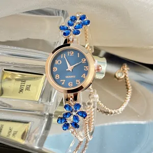 Detailed view of women quartz watch with blue crystal flowers and rose gold pull chain strap.