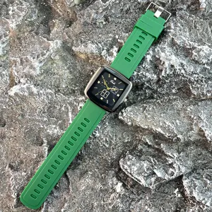 Nahaufnahme des quadratischen Zifferblatts Quarzuhr mit grünem Silikonarmband im Freien.