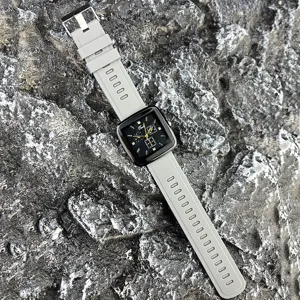 Detailansicht der quadratischen Quarzuhr mit grauem Silikonarmband auf Steinhintergrund.