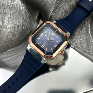 Reloj de cuarzo cuadrado con correa de silicona azul y bisel de oro rosa en detalle.