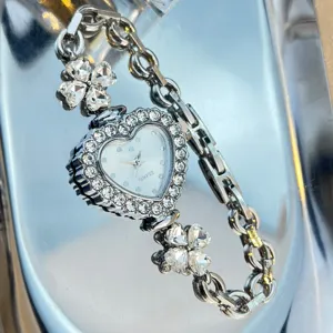 Silver tone heart-shaped quartz watch with crystal clover charms and rhinestone bezel.