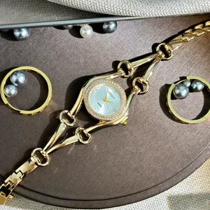Nahaufnahme einer luxuriösen goldenen Quarzuhr mit Strasszifferblatt und Perlenringen.