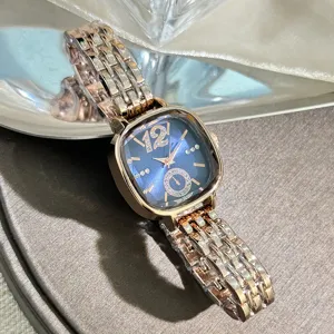Closeup of square glass quartz watch, blue dial with rhinestones and elegant rose gold metal bracelet.