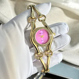 Luxus goldfarbene Damen Quarzuhr mit rosa Strass Zifferblatt und Pferdegebiss Armband.
