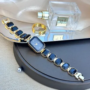 Detailansicht der luxuriösen Damen Armbanduhr mit quadratischem schwarzem Edelstein und Goldkette.