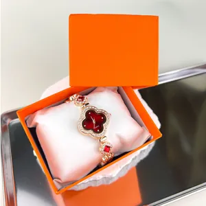 Primo piano dettagliato di orologio al quarzo trifoglio di lusso in scatola regalo arancione.