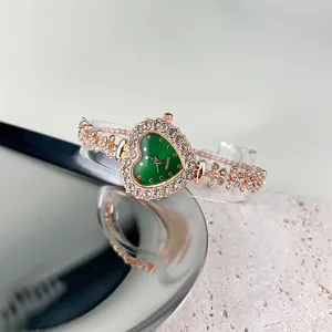 Nahaufnahme Damenuhr Quarzuhr, herzförmiges grünes Zifferblatt mit Strass und Blumenarmband.