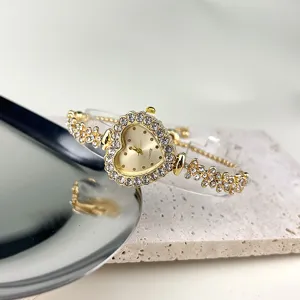 Nahaufnahme des herzförmigen Strass-Quarzuhr-Details mit funkelnden Schmucksteinen.