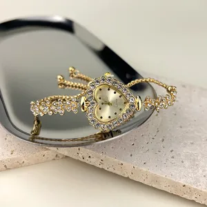 Nahaufnahme einer goldenen Herz-Strass-Quarzuhr auf einem eleganten silbernen Tablett.